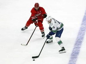 Elias Pettersson skates with the puck while defending Jordan Staal in the first period