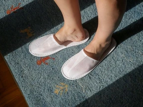 A traveler wears slippers on a carpeted hotel room floor