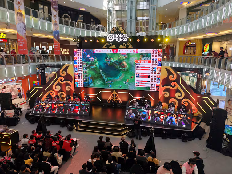 Players sat on a stage competing in an Honor of Kings tournament as an audience watched.