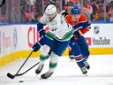 Elias Pettersson drives the puck through the neutral zone with Oilers' Kasperi Kapanen in pursuit during the third period in Edmonton on Tuesday night